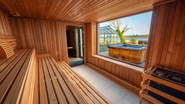 Eine Holzsauna mit einem Whirlpool im Hintergrund