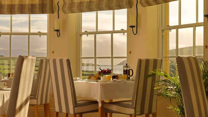 Ein Esszimmer mit Tisch und Stühlen und vielen Fenstern