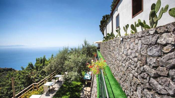 Eine Steinmauer führt zu einem Garten mit Blick auf den Ozean