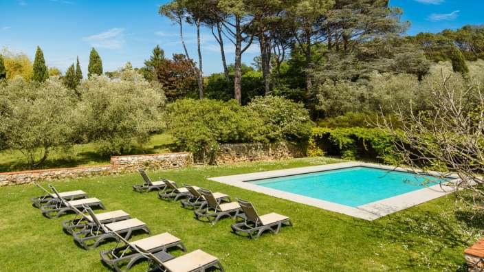 Liegestühle stehen neben einem großen Swimmingpool