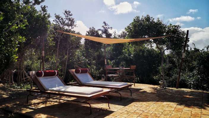 Zwei Liegestühle auf einer Terrasse mit einem Sonnenschirm