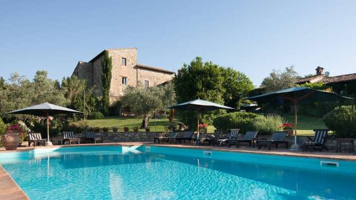 Ein großer Swimmingpool mit Liegestühlen und Sonnenschirmen umgeben