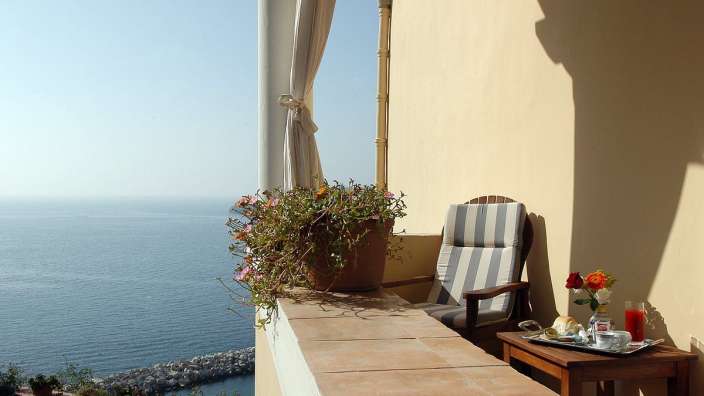 Ein Stuhl sitzt auf einem Balkon mit Blick auf das Meer