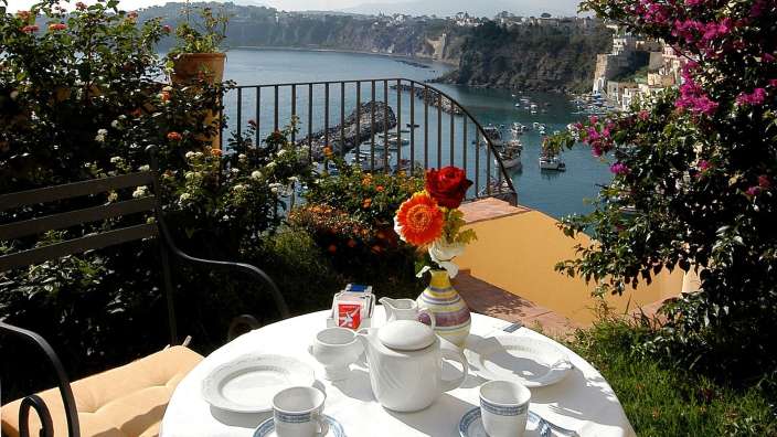 Ein Tisch mit Kaffeetassen und einer Kaffeekanne auf einem Balkon mit Blick auf den Ozean