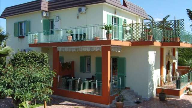 Ein weißes Haus mit grünen Fensterläden und einem Balkon