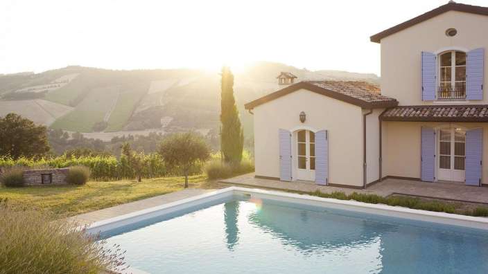 Ein weißes Haus mit blauen Fensterläden und einem Swimmingpool vorne