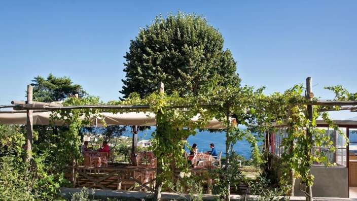 Eine Gruppe von Menschen sitzt an einem Tisch in einem Restaurant mit Blick auf das Meer