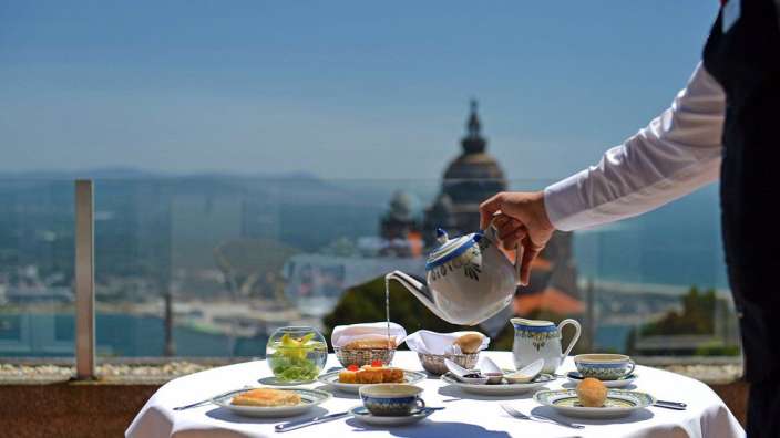 Ein Mann gießt Tee aus einer Teekanne auf einen Tisch