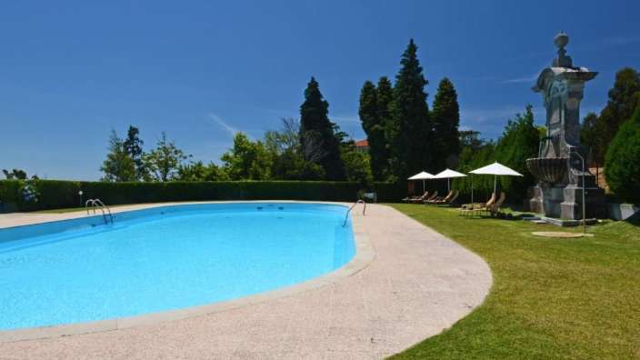 Ein großer Swimmingpool mit Liegestühlen und Sonnenschirmen umgeben
