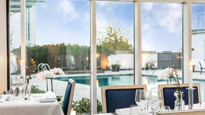 Tische und Stühle in einem Restaurant mit Blick auf einen Pool