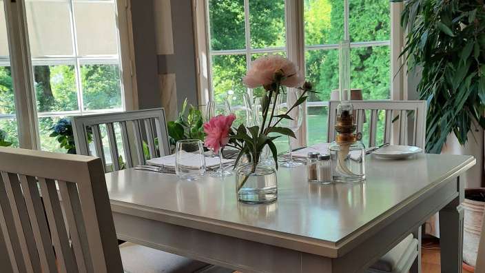 Ein Tisch mit einer Vase mit einer rosa Blume darauf