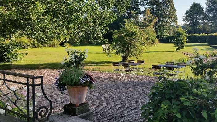 Ein Blumentopf sitzt auf einem Stein neben einem Tisch und Stühlen