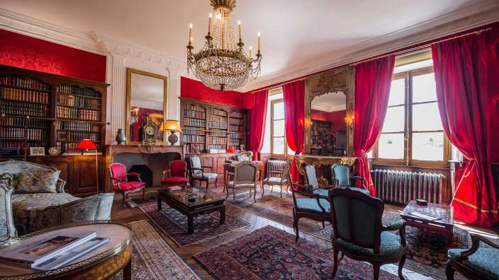 Ein Wohnzimmer mit vielen Möbeln und roten Vorhängen