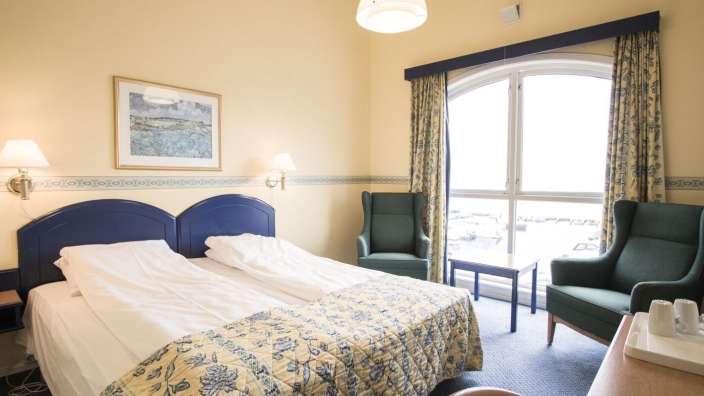 Ein Hotelzimmer mit zwei Betten und einem Stuhl