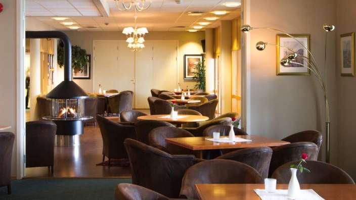 Ein Restaurant mit vielen Tischen und Stühlen und einem Kamin