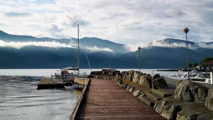Ein hölzerner Pier mit einem Boot darauf und Bergen im Hintergrund .
