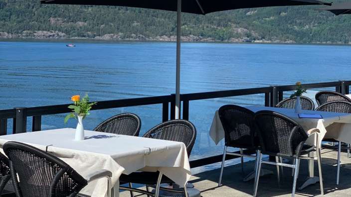 Tische und Stühle stehen unter einem schwarzen coca-cola-Sonnenschirm