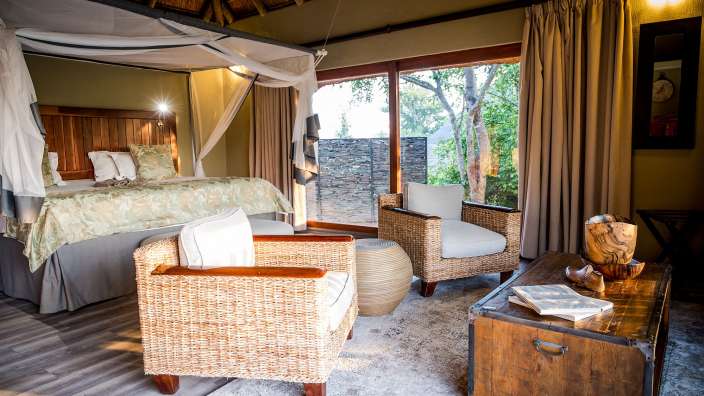 Ein Schlafzimmer mit einem Himmelbett und zwei Stühlen