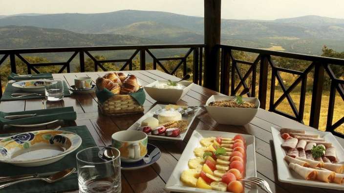 Ein Tisch mit verschiedenen Speisen und Getränken auf einem Balkon mit Blick auf die Berge