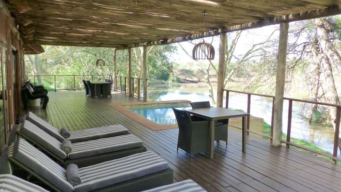 Ein Deck mit Liegestühlen und einem Tisch mit Blick auf einen Fluss