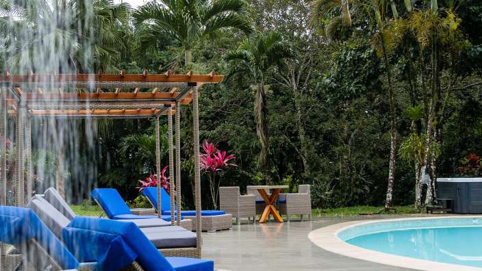 Liegestühle neben einem Pool mit einem Wasserfall im Hintergrund