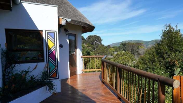 Ein weißes Haus mit einem Strohdach und einem Holzdeck