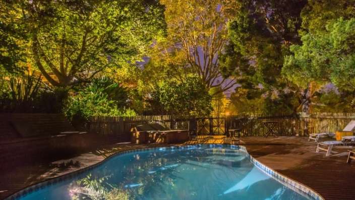 Ein großer Swimmingpool mit Bäumen im Hintergrund bei Nacht