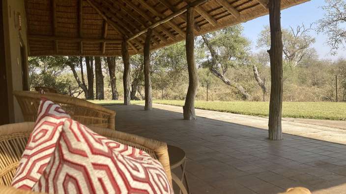 Ein rot-weiß gemusterter Kissen sitzt auf einem Korbstuhl