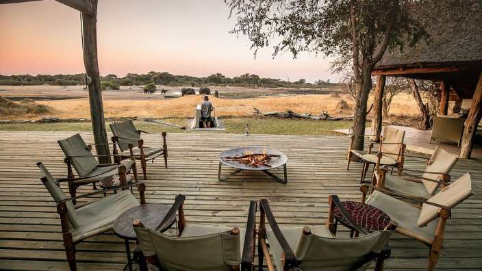 Ein Deck mit Stühlen und einem Feuer und Elefanten im Hintergrund