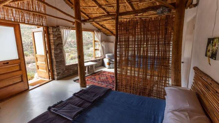 Ein Bett in einem Raum mit Strohdach