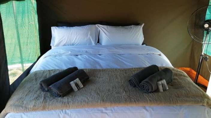 Ein Bett in einem Zelt mit Handtüchern und einem Ventilator
