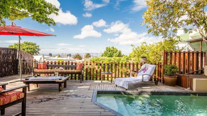 Ein Holzdeck mit einem Swimmingpool und einem roten Regenschirm