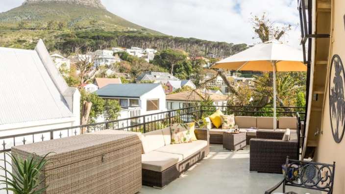 Ein Balkon mit Möbeln und einem Sonnenschirm mit einem Berg im Hintergrund