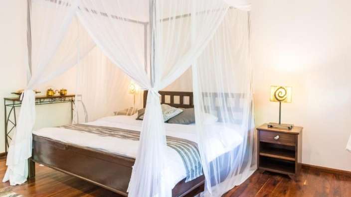 Ein Schlafzimmer mit Himmelbett und weißen Vorhängen