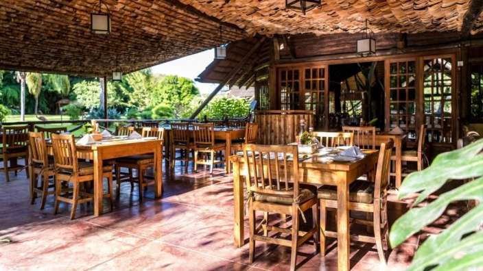 Ein Restaurant mit Holztischen und Stühlen und einem Strohdach