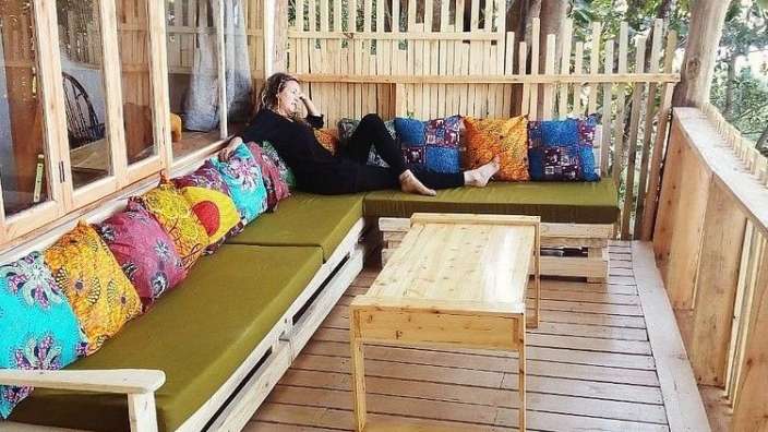 Eine Frau sitzt auf einer grünen Couch mit bunten Kissen