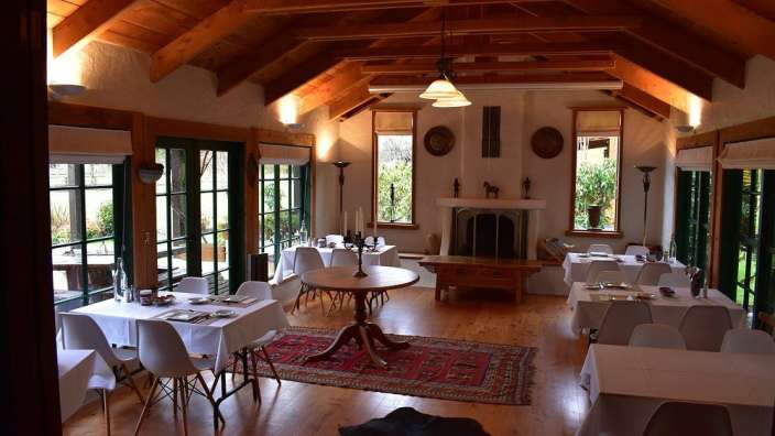 Ein Esszimmer mit vielen Tischen und Stühlen und einem Kamin