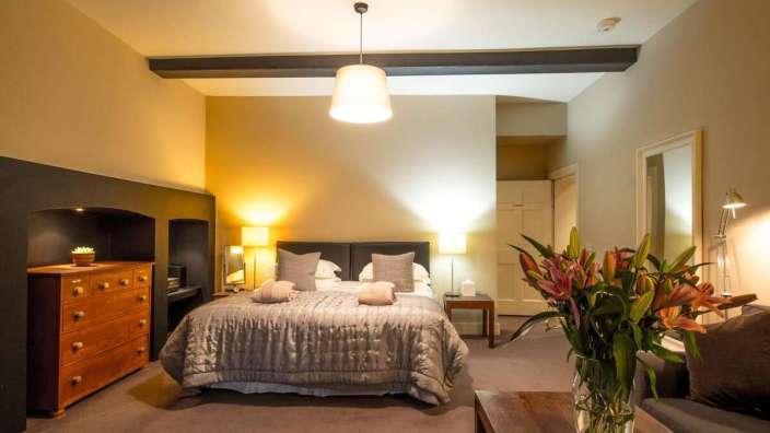 Ein Schlafzimmer mit einem großen Bett und einer Vase mit Blumen