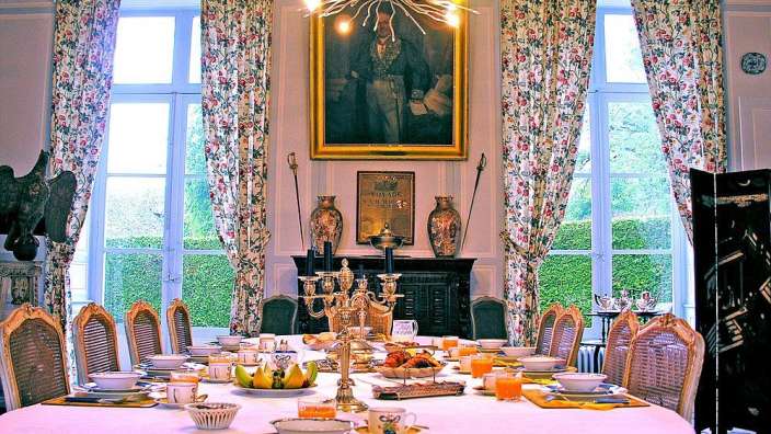 Ein Esszimmer mit einem großen Tisch und einem Gemälde über dem Tisch