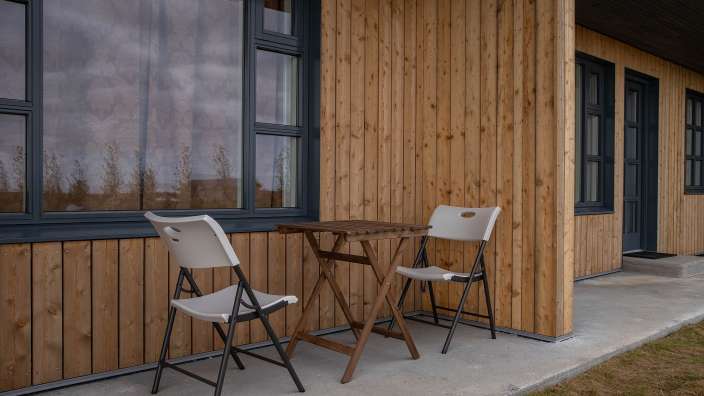 Ein Tisch und zwei Stühle vor einem Holzgebäude
