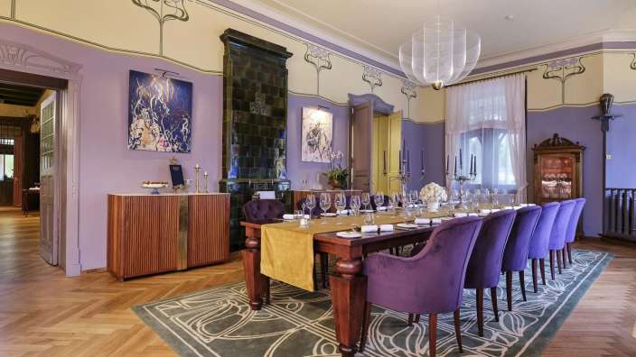 Ein Esszimmer mit einem langen Tisch und lila Stühlen