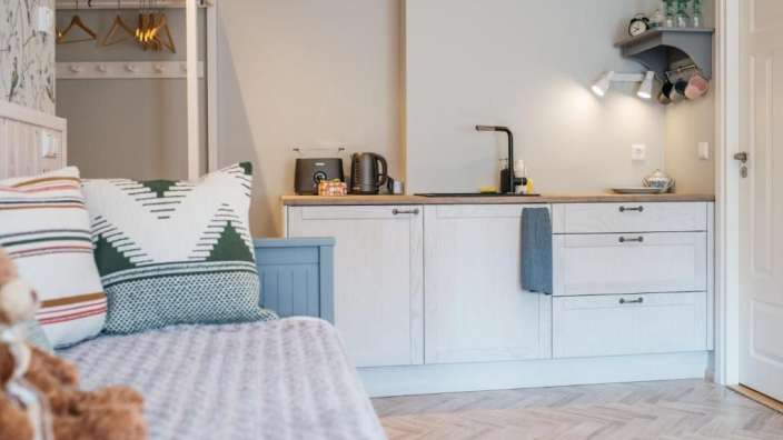 Eine kleine Küche mit weißen Schränken und einem Wasserkocher