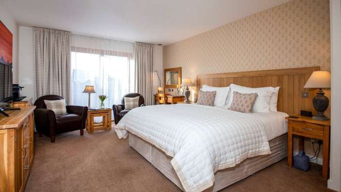 Ein Hotelzimmer mit einem großen Bett und zwei Stühlen