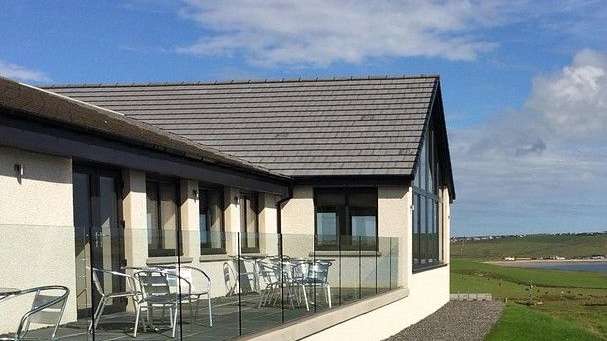 Ein Haus mit einem Balkon mit Stühlen und Tischen darauf