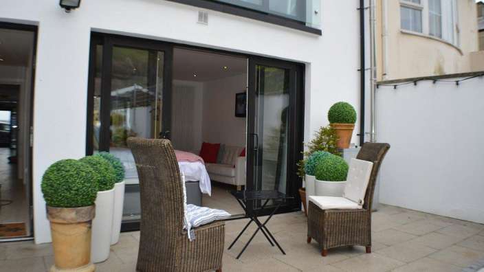 Eine Terrasse mit Stühlen und einem Tisch vor einem weißen Haus