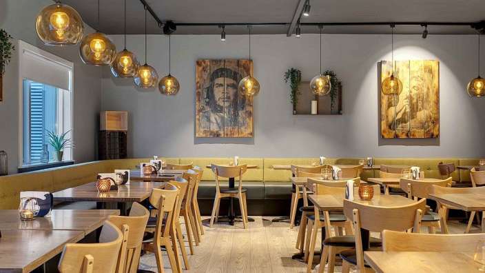 Ein Esszimmer mit Tischen und Stühlen und einem Gemälde an der Wand