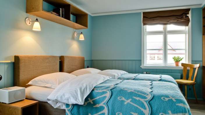 Ein Schlafzimmer mit zwei Betten und einer blauen Decke mit Ankern darauf