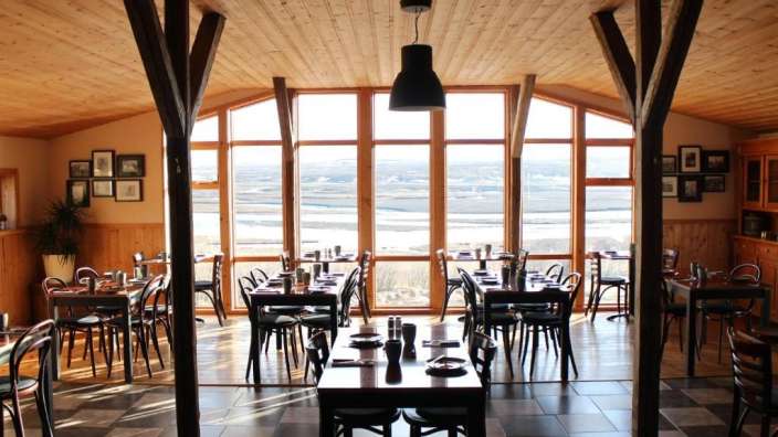 Ein Restaurant mit vielen Tischen und Stühlen und einem großen Fenster