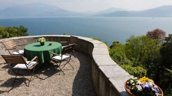 Ein Tisch und Stühle auf einem Balkon mit Blick auf einen See