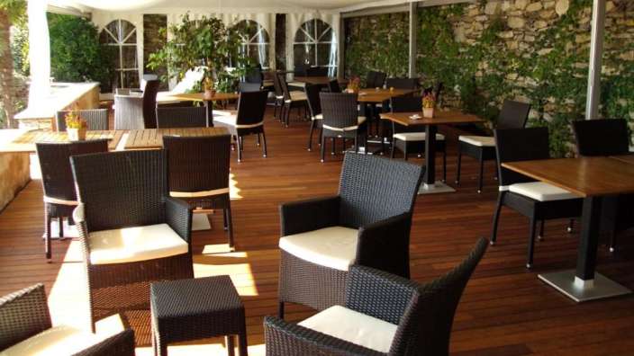 Tische und Stühle auf einem Holzdeck unter einem Zelt